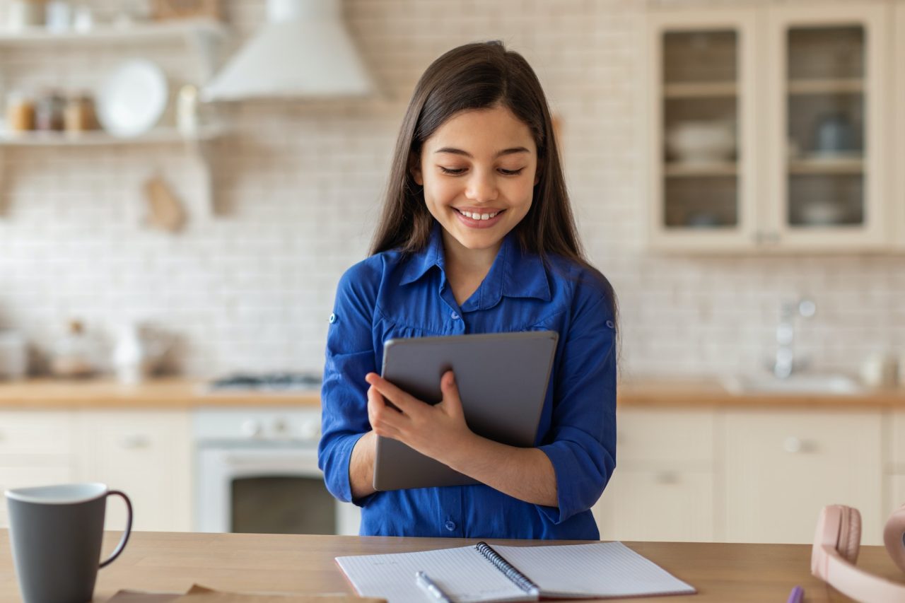 Schoolgirl Using Tablet Computer At Home Learning Having Fun Online